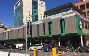 Fachada moderna del centro comercial Paseo El Tamarugo, con el hotel Hyatt Place de fondo y locales como Danés y Starbucks Coffee en primer plano. Estacionamiento de autos y motos al frente