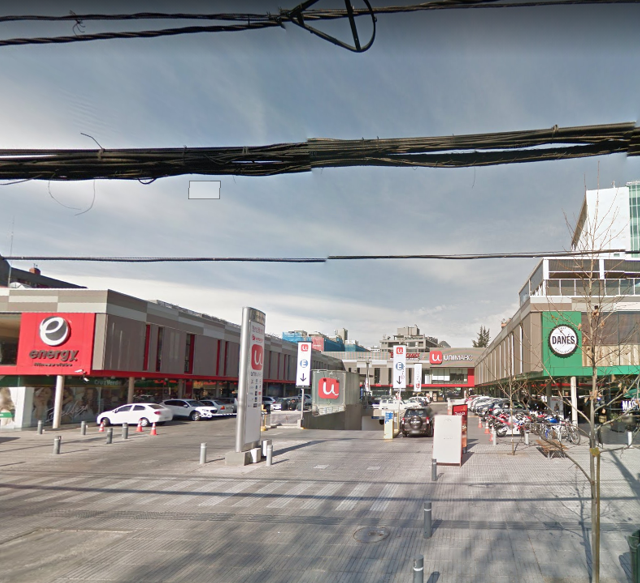 Vista frontal del centro comercial Paseo El Tamarugo, con señaléticas de Unimarc, Energy Fitness y Danés Café, estacionamiento y hotel Hyatt Place al fondo, en un entorno urbano con tránsito de vehículos y personas