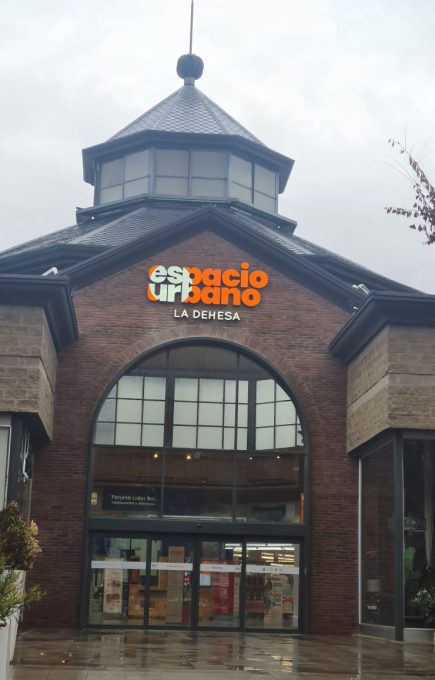 Ingreso al centro comercial Espacio Urbano La Dehesa, destacando su arquitectura de ladrillo y techo vidriado, con el logo visible sobre la entrada