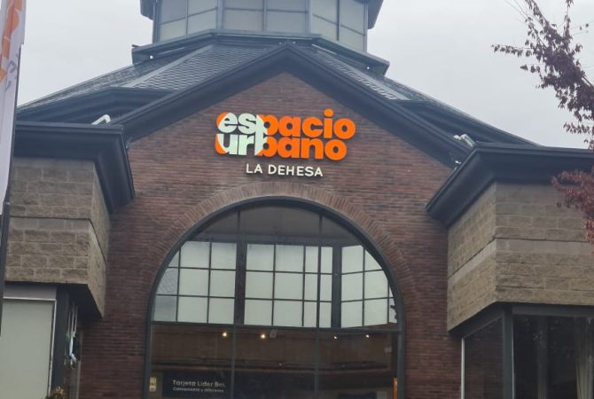 Ingreso al centro comercial Espacio Urbano La Dehesa, destacando su arquitectura de ladrillo y techo vidriado, con el logo visible sobre la entrada
