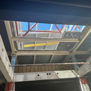 Vista superior de la estructura de techumbre y el avance de la construcción, con luz natural entrando por la cubierta abierta