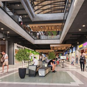 Vista interior de un centro comercial moderno con tiendas como Pandora y Dunkin Donuts, personas caminando y descansando en bancas, iluminación cálida y techos altos con estructura abierta.