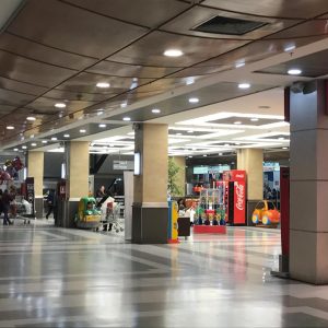Vista de un pasillo interior en un centro comercial, con personas caminando, carritos de supermercado y áreas de juegos infantiles junto a tiendas como La Polar.