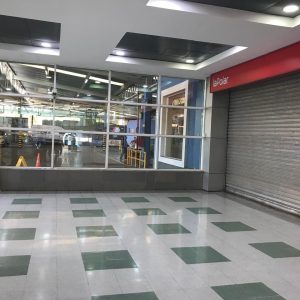 Vista desde el interior del mall hacia el estacionamiento vehicular, con señalética de tarifas y un local de La Polar con cortina metálica cerrada.