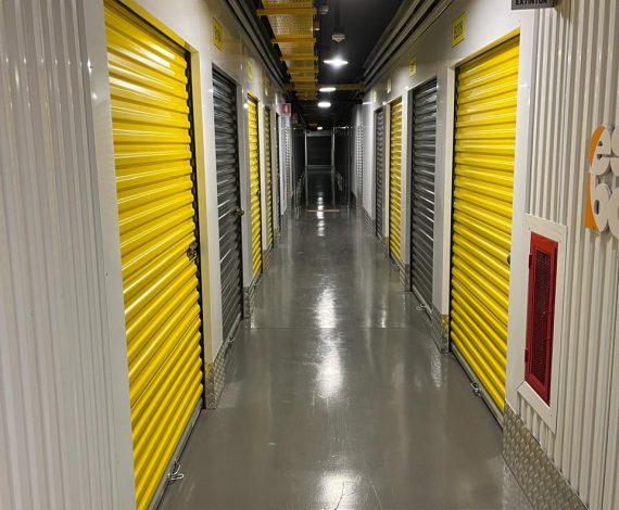 Pasillo interior de bodegas de autoalmacenaje, con puertas enrollables amarillas y ambiente bien iluminado