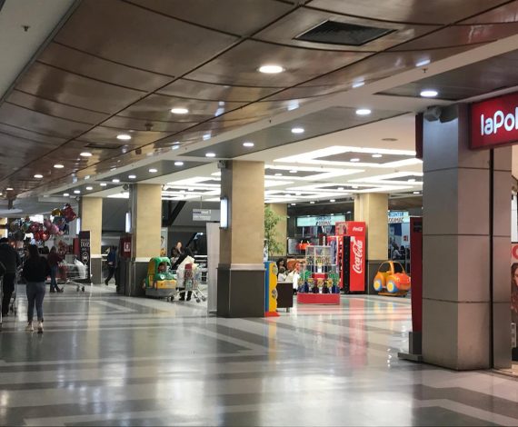 Vista del interior del centro comercial Espacio Urbano, mostrando tiendas como La Polar, juegos infantiles, carros de supermercado y personas recorriendo el lugar.